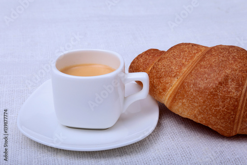 Crispy fresh croissants and cup of coffee espresso on a white background, morning breakfast, selective focus