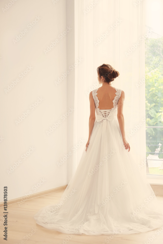 Bride in a beautiful wedding dress standing near window Bride in a beautiful wedding dress standing near window