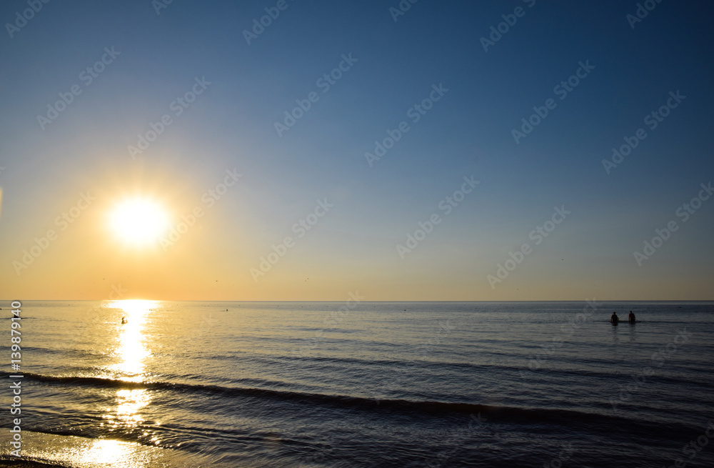 Sea sunset. People bathe in the evening at sunset in the sea.