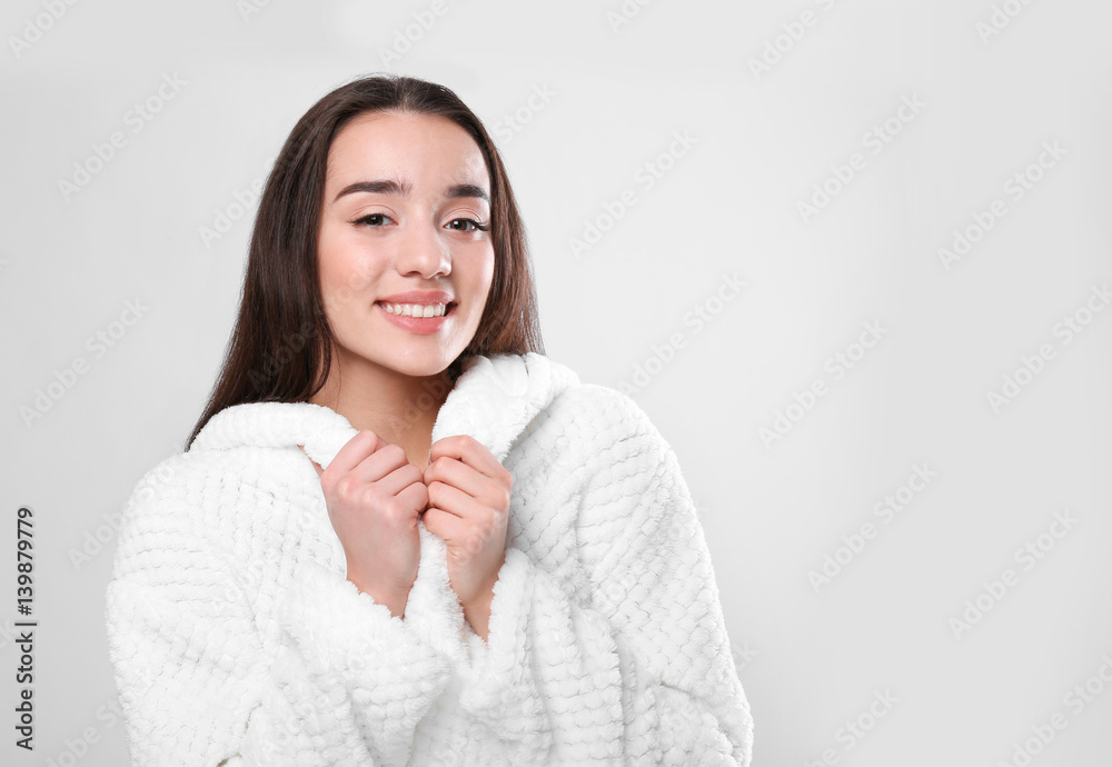 Beautiful young woman in bathrobe on light background Beautiful young woman in bathrobe on light background