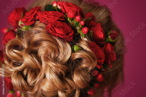 Closeup view of beautiful female hairstyle with flowers on color background