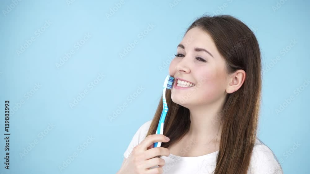 Woman holding brush for teeth cleaning. Happy positive smiling girl with manual toothbrush. Oral daily hygiene. Studio shot blue background 4K ProRes HQ codec Woman holding brush for teeth cleaning. Happy positive smiling girl with manual toothbrush. Oral daily hygiene. Studio shot blue background 4K ProRes HQ codec