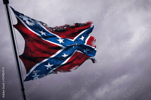 closeup of ripped tear grunge old waving confederate flag of the national states of america us, fabric texture american symbol on cloudy sky, dark mystery style atmosphere photo