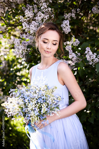 Girl with a lilac bouquet of lilac in the garden.  Lilies of the valley and forget-me-nots