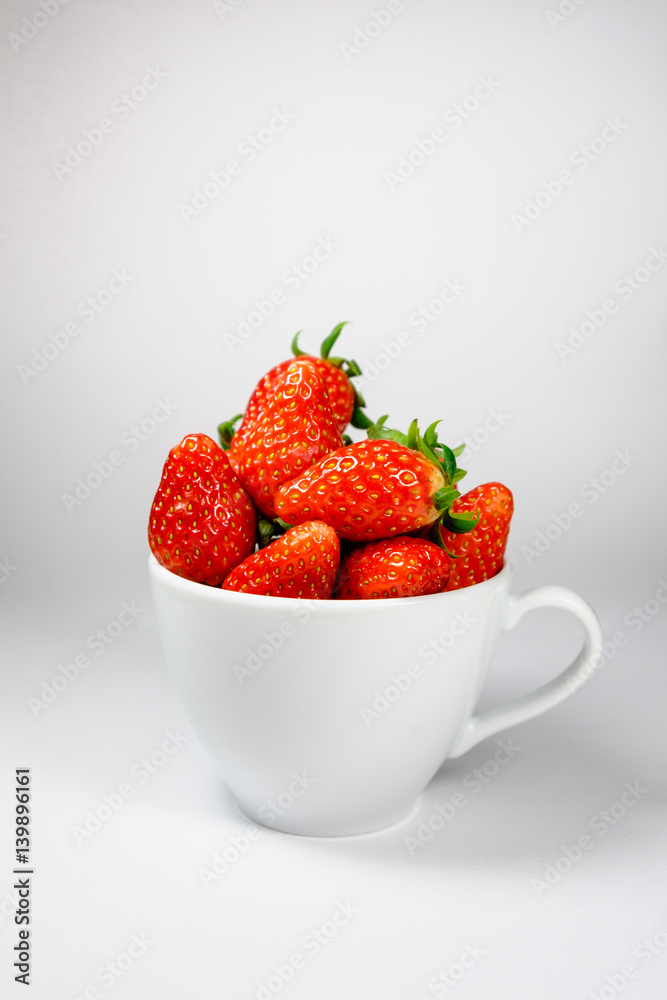 Strawberry in the white coffee cup on a white background Strawberry in the white coffee cup on a white background
