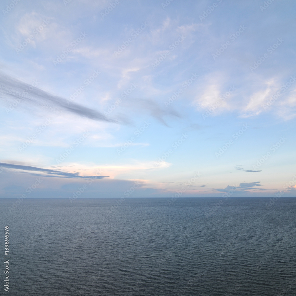 cloudy blue sky leaving for horizon above a blue surface of the sea