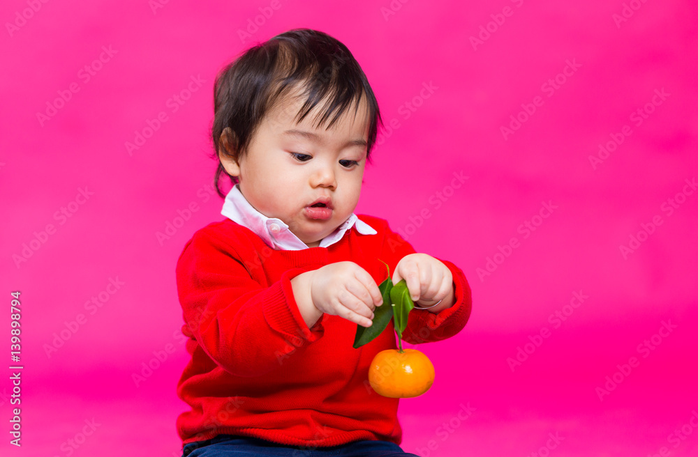 Asian baby holding a tangerine Asian baby holding a tangerine