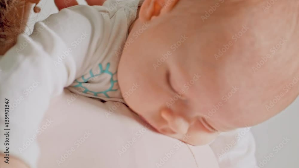 Beautiful baby in her mothers hands falling asleep