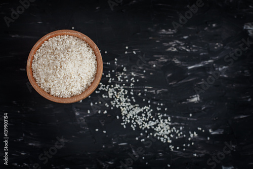 Bowl of raw rice on black background. The concept of healthy eating and vegetarianism.