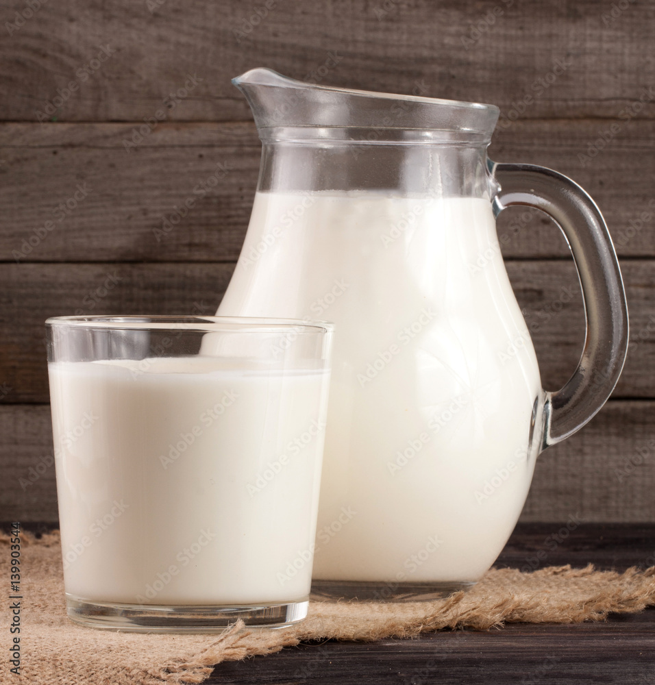 jug and glass of milk on a wooden background jug and glass of milk on a wooden background