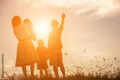 silhouette of happy family father mother and son playing outdoors at sunset
