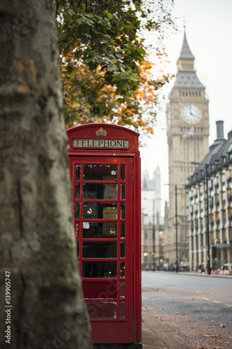 Close-up view of an old red telephone box, blurred big ben and house of parliament in the background, London, United Kingdom.