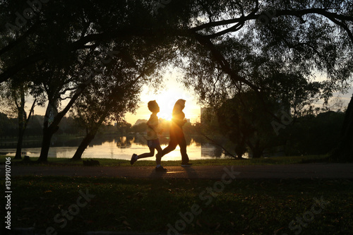 Silhouette of people jogging in park during morning sunrise