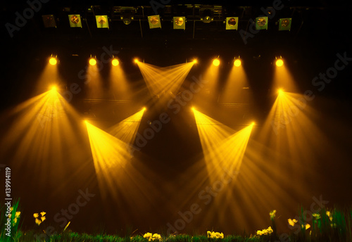 The yellow light from the spotlights through the smoke at the theater during the performance. Lighting equipment.