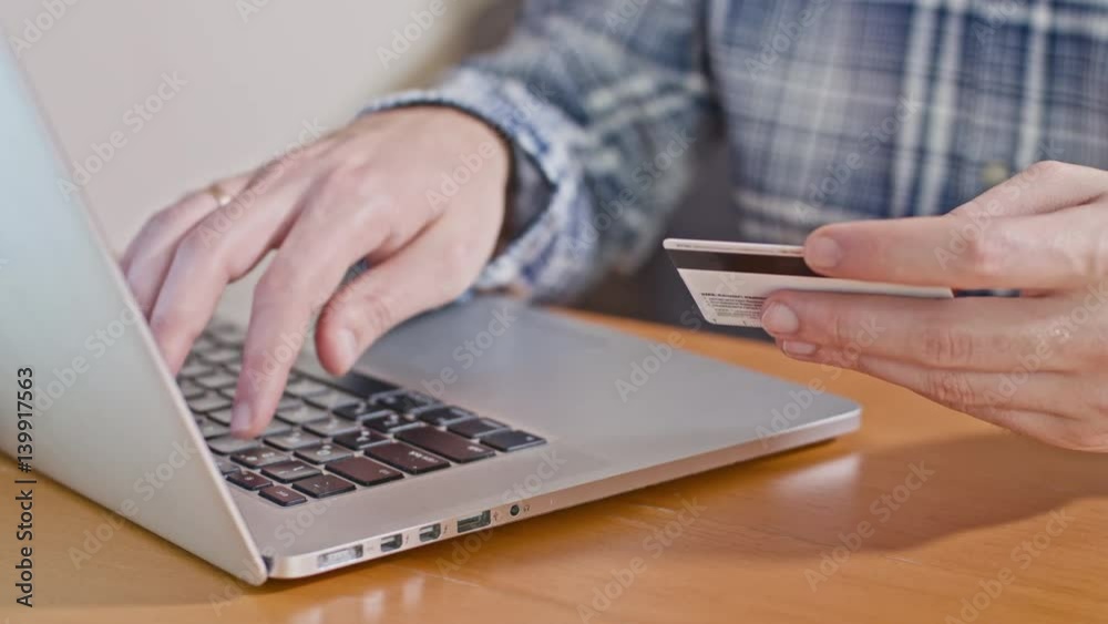 Close-up view of man's hands typing credit card number Close-up view of man's hands typing credit card number