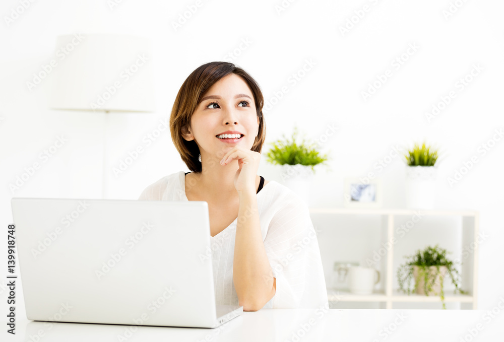 young woman with laptop and thinking in living room young woman with laptop and thinking in living room