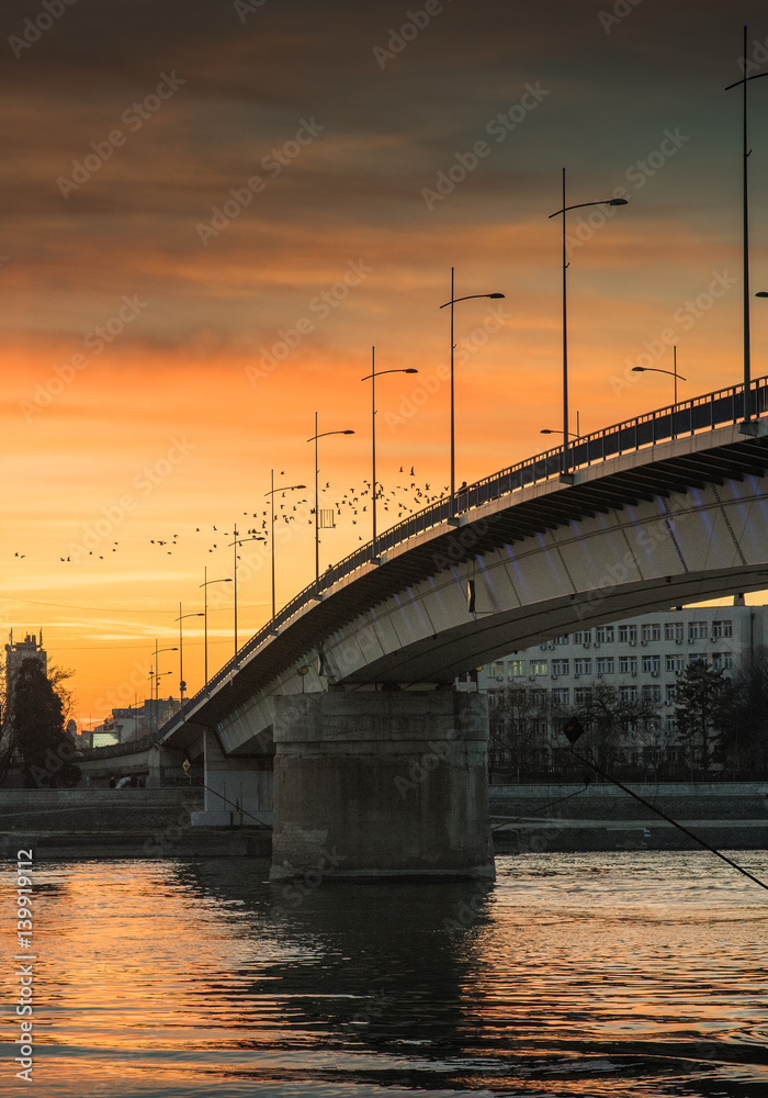 Beautiful warm sunset on the city panorama with buildings and colorful sky over the bridge and river