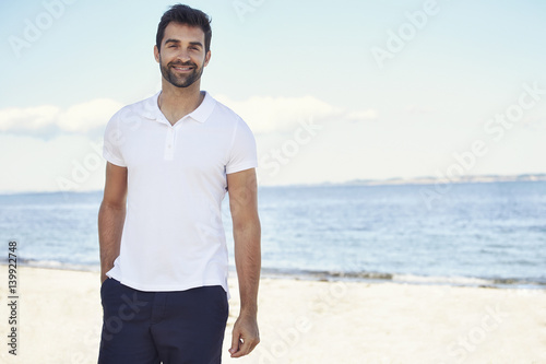 Casual guy on beach, smiling to camera