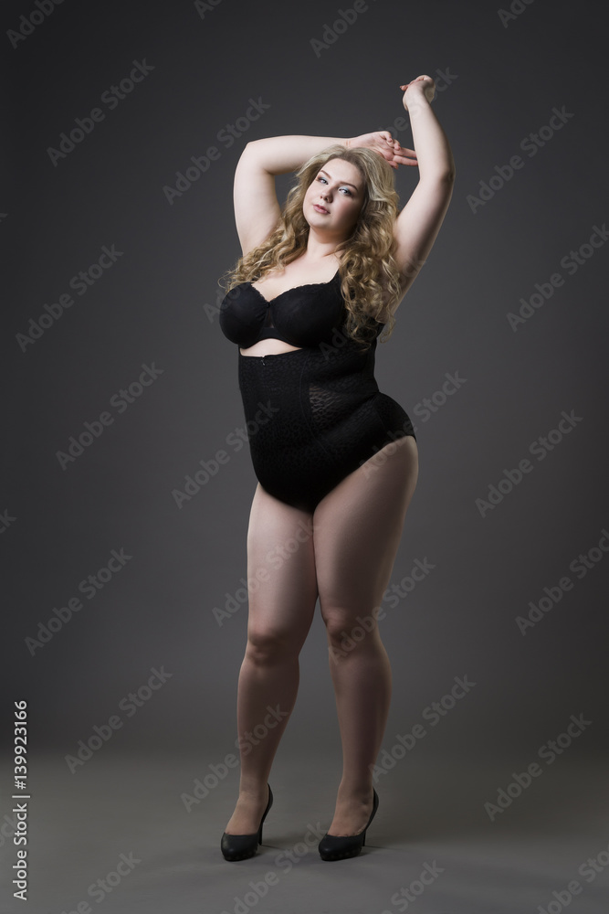 Young beautiful blonde plus size model in shapewear, xxl woman in slimming underwear on gray studio background Young beautiful blonde plus size model in shapewear, xxl woman in slimming underwear on gray studio background