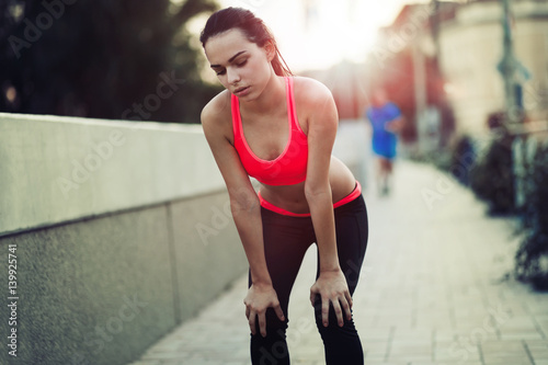 Beautiful female jogger tired after running