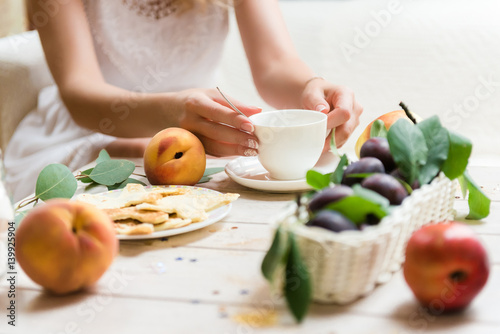 A nice fresh breakfast for a young girl, bright fruit and a neat white cup