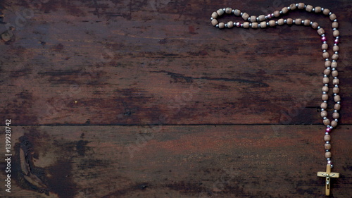 a rosary with beads on wooden textured background. Place for text photo