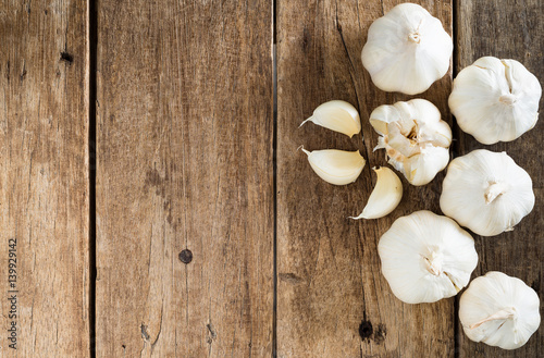 peeled white garlic on brown wood table texture with copy  space, top view
