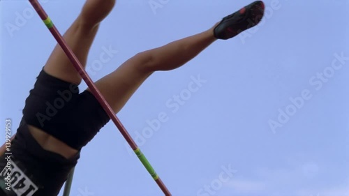 Girl pole vaulting in slow motion, seen from below bar photo