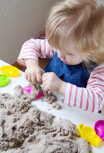 Little baby girl age of 1,11 years play with kinetic sand