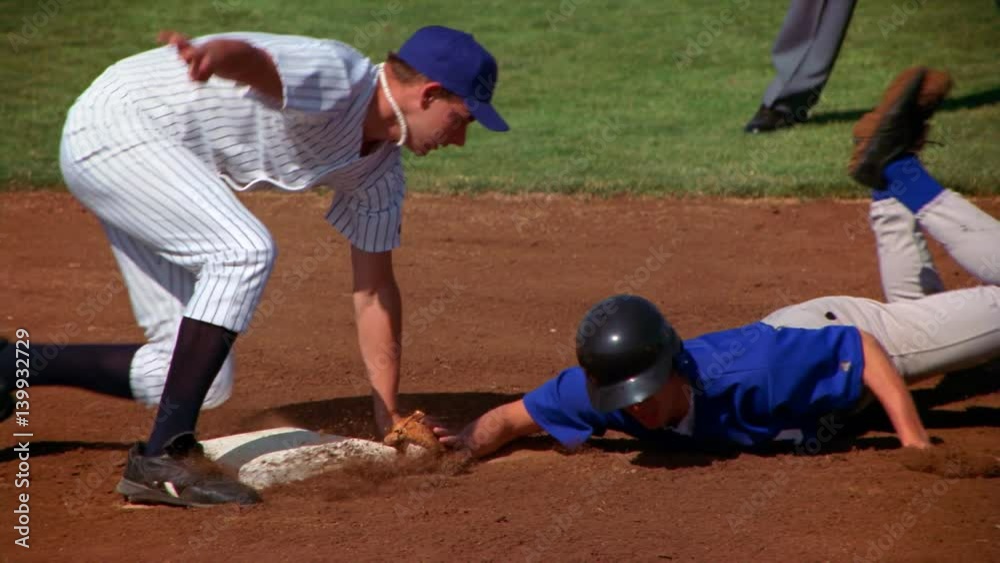 Runner sliding toward base, baseman stooping to tag