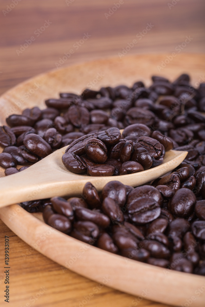Coffee beans on a wooden spoon and plate on table Coffee beans on a wooden spoon and plate on table