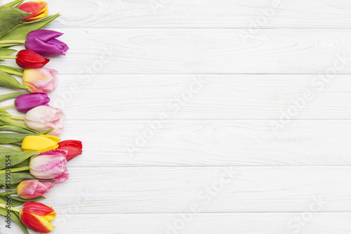 colorful tulips on white wooden background.