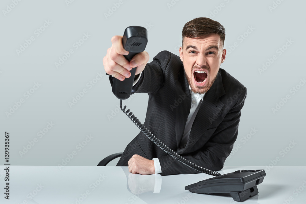 Naklejka premium young man dials the phone number while sitting in the office