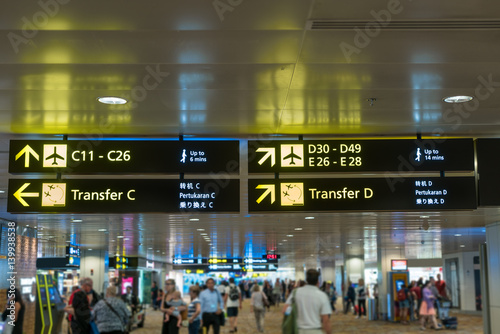 Yellow information sign at airport with gate number for departure and transfer flights in terminal at airport.