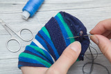 Hand with a needle and thread darning a sock. Handmade.