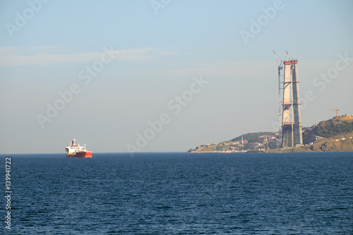 Container ship passing the new Third Bridge that is under construction on the Bosphorus, Istanbul, Turkey.