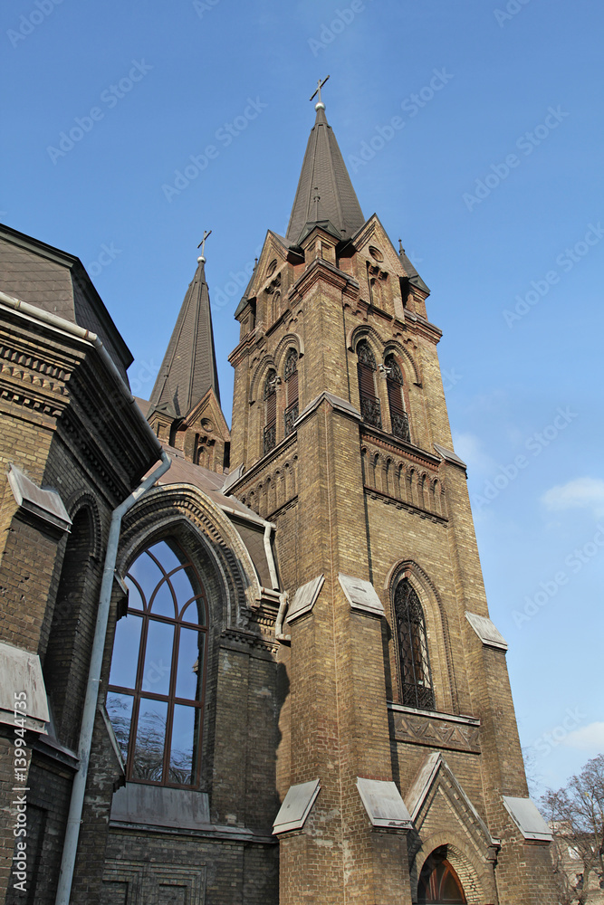 Part of the skyward Catholic cathedral with two pointed towers is crowned with crosses.
