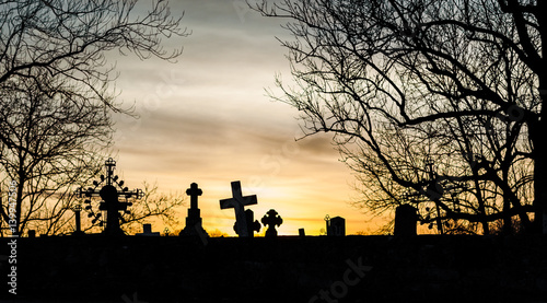 Crosses on the graves of the old cemetery silhouette in the rays of the evening sun photo