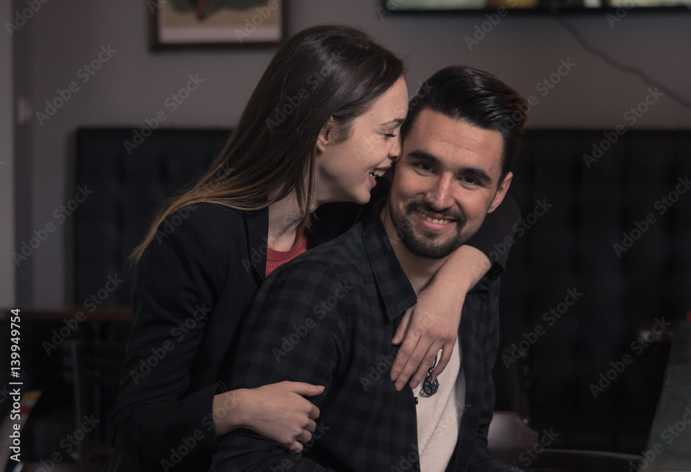 young woman hugging man, looking at camera smiling