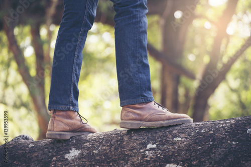 Close ups of tourist legs .Lonely man wearing jeans and brown boots,he standing on a tree.