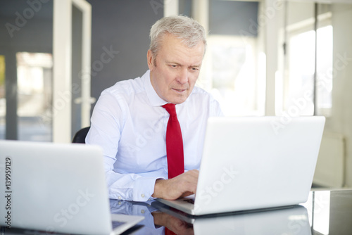 Financial analysis. Senior businessman working hard on laptop at office © sepy