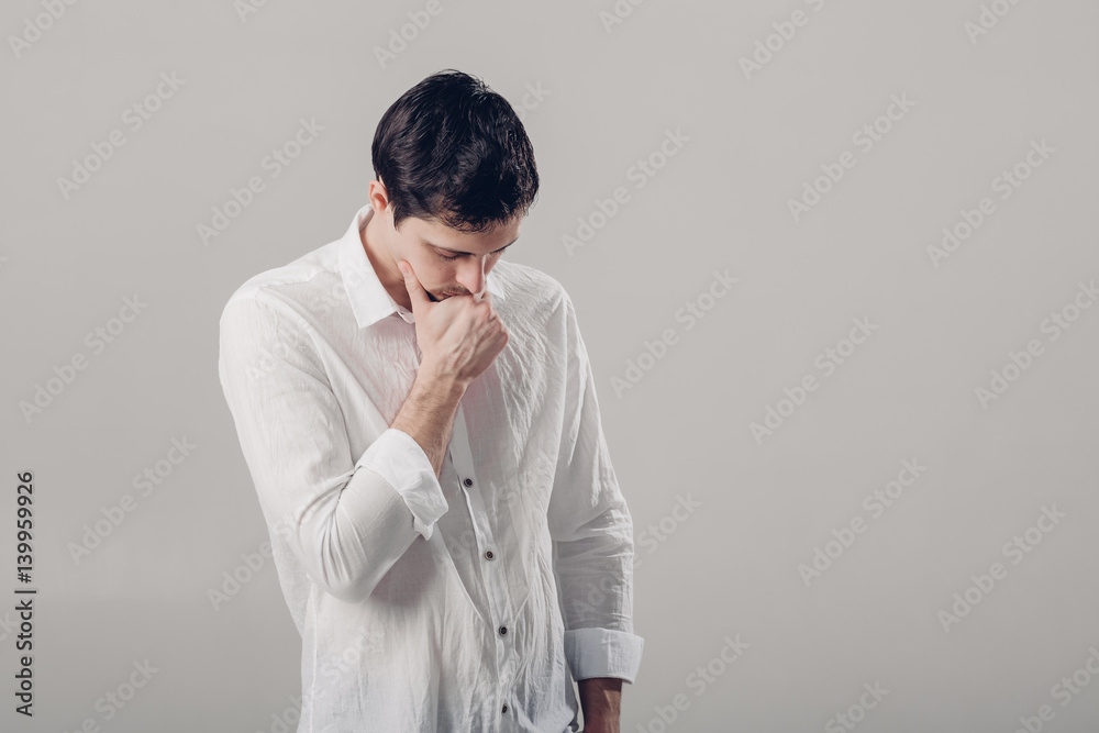 portrait of handsome young pensive man in white shirt on gray ba portrait of handsome young pensive man in white shirt on gray ba