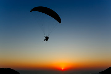 Fotobehang Luchtsport Paraglider silhouet bij oranje zonsondergang  © aleksey ipatov