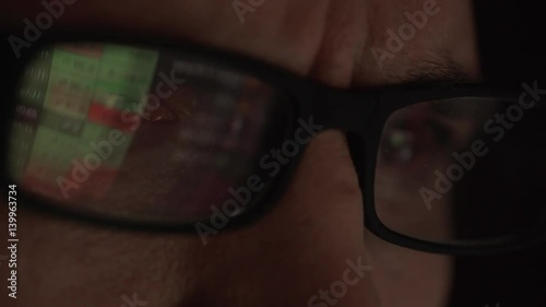 Spreadsheets reflecting in glasses of Caucasian male. Close up footage