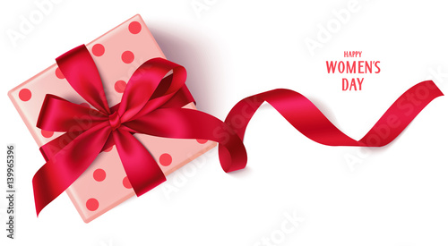 Decorative gift box with red bow and long ribbon. Happy Women's Day text. Top view