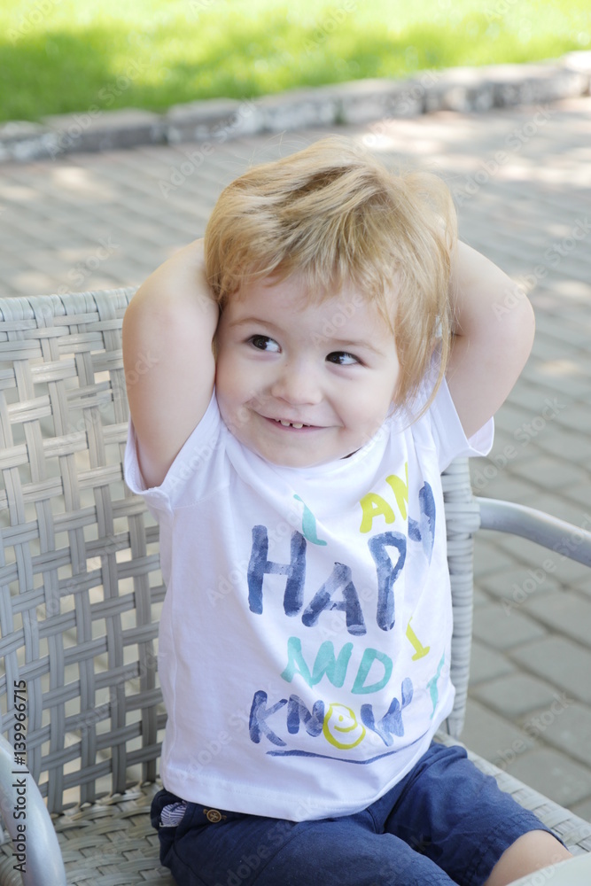 Cute Boy with smiling eyes posing to the camera. Toddler baby boy with  blonde hair sitting