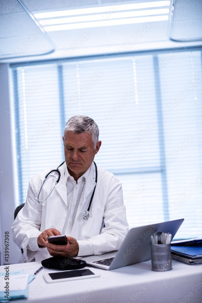 Fototapeta premium Doctor sitting at tablet and using mobile phone