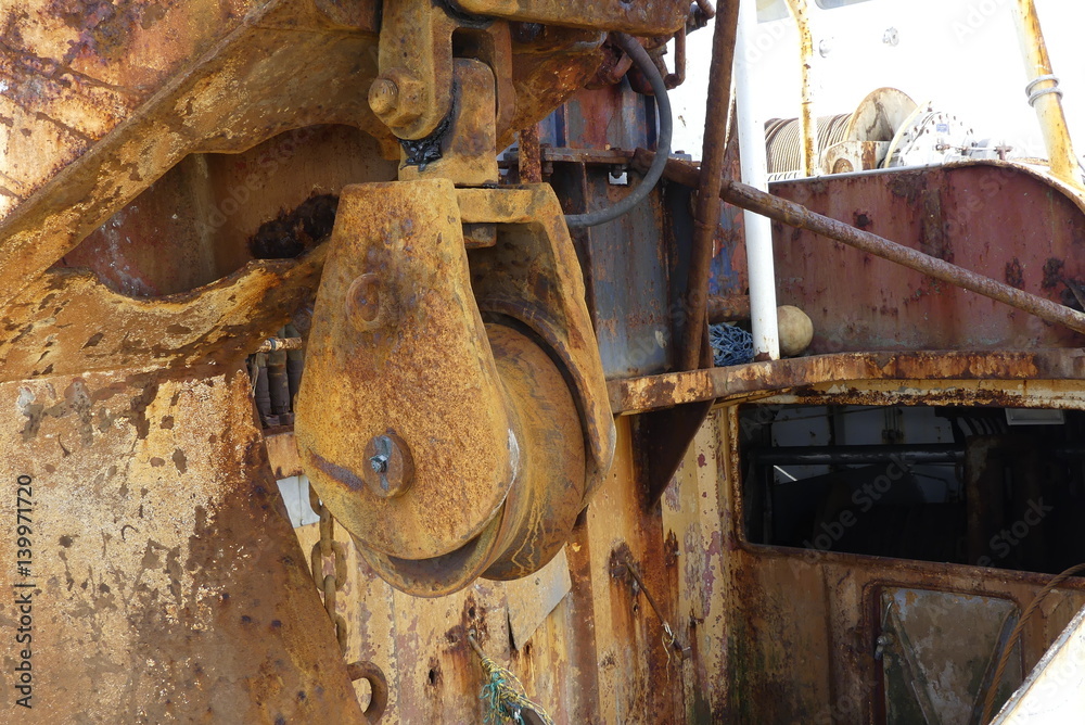 Closeup of trawler cable warp pulley on the stern of a steel fishing boat with rust and corrosion by salt water Closeup of trawler cable warp pulley on the stern of a steel fishing boat with rust and corrosion by salt water