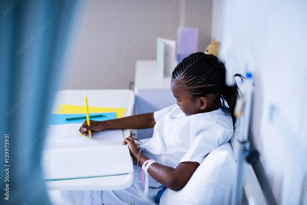 Naklejka premium Patient writing on the book while sitting at hospital
