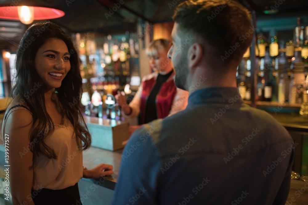Friends interacting at counter in bar Friends interacting at counter in bar